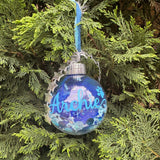 Blue ornament with 'Archie' text hanging on a Christmas tree