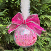 Decorative ornament with pink bow and 'Daisy' text, hanging on a tree.