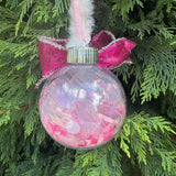 Decorative Christmas ornament with pink confetti on a green tree