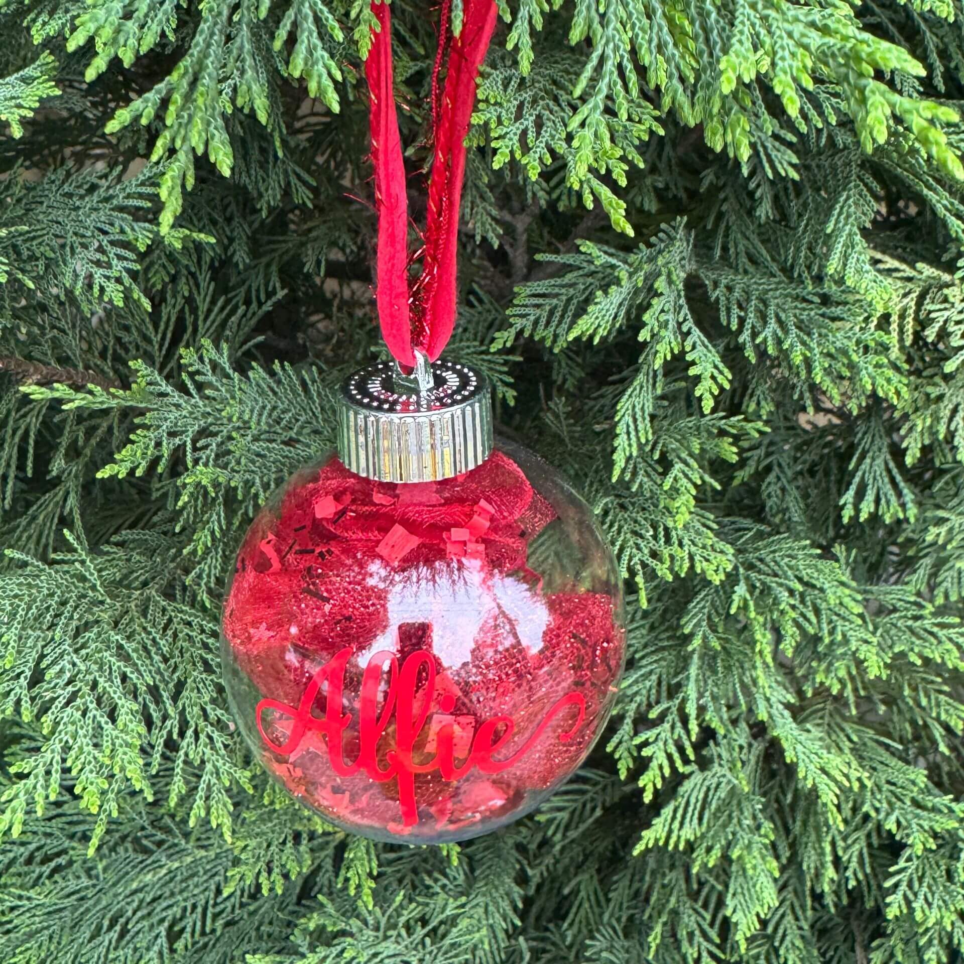 Red Christmas ornament with 'Allee' on a tree