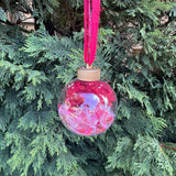 Decorative Christmas ornament with pink and purple design hanging on a tree.