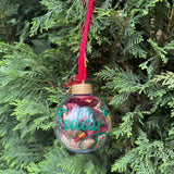 Decorative Christmas ornament with 'Teddy' text hanging on a tree