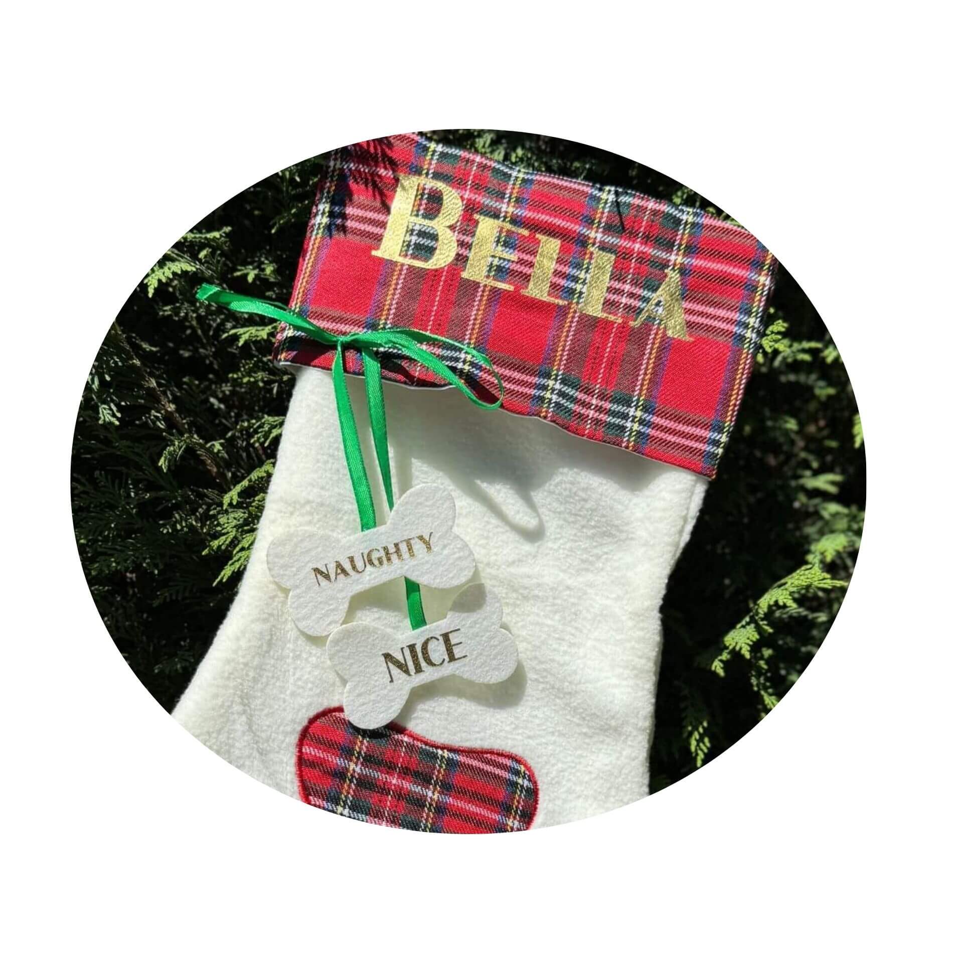 Dog stocking with plaid top and 'Bella' tag, surrounded by greenery