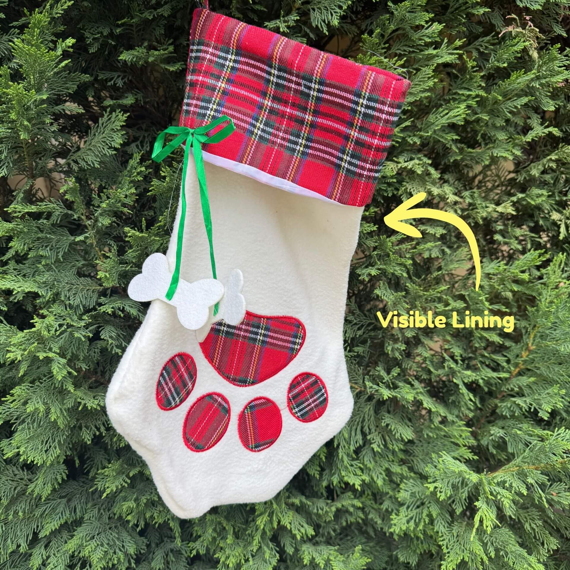 Christmas stocking with plaid design and paw print on a green bush