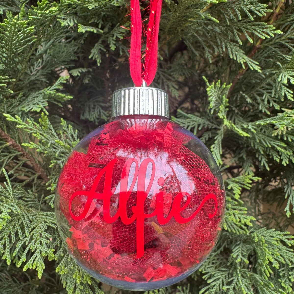 Red Christmas ornament with 'Alfie' on a tree